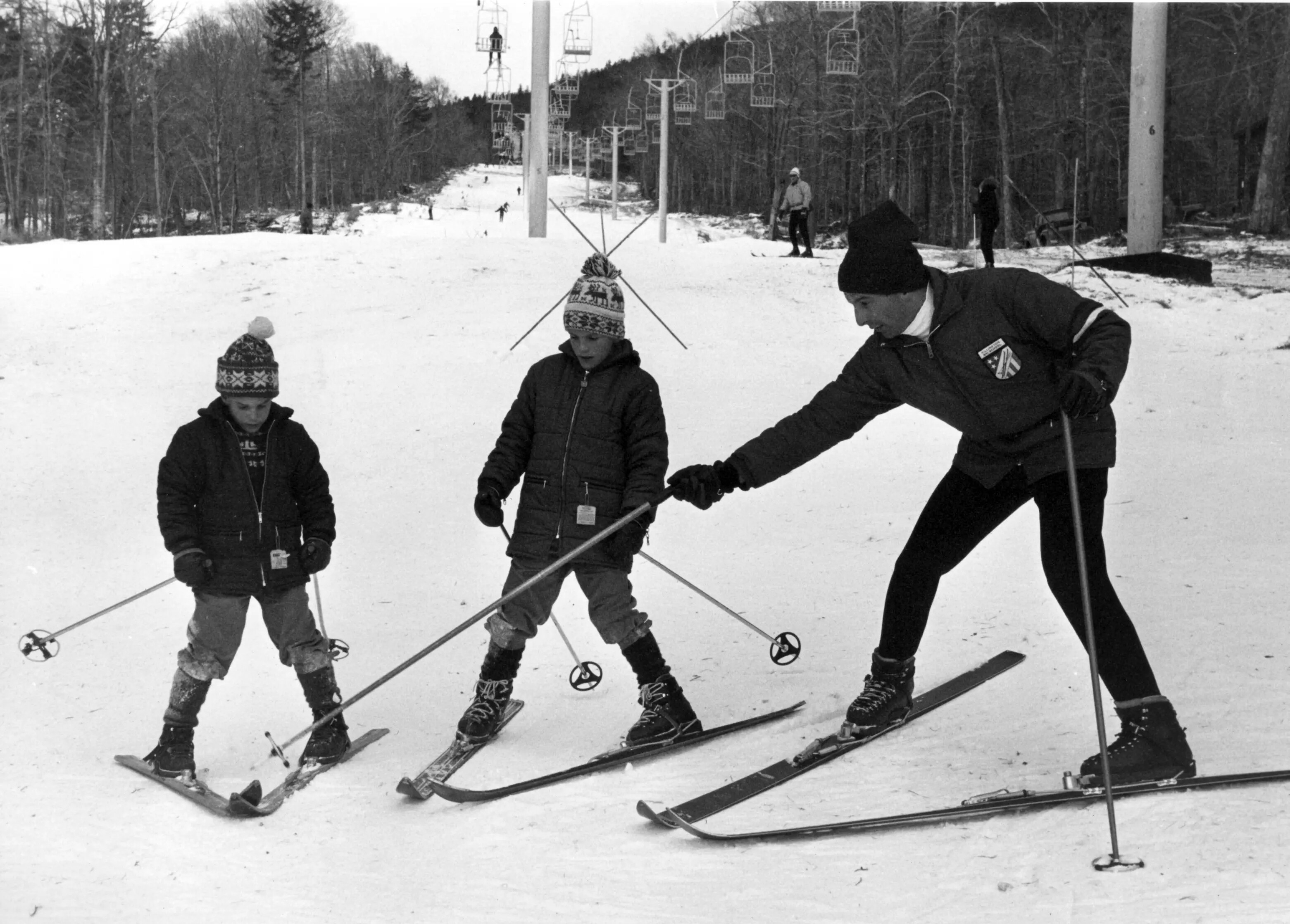 Two children learn to ski from an instructor on a snowy slope.