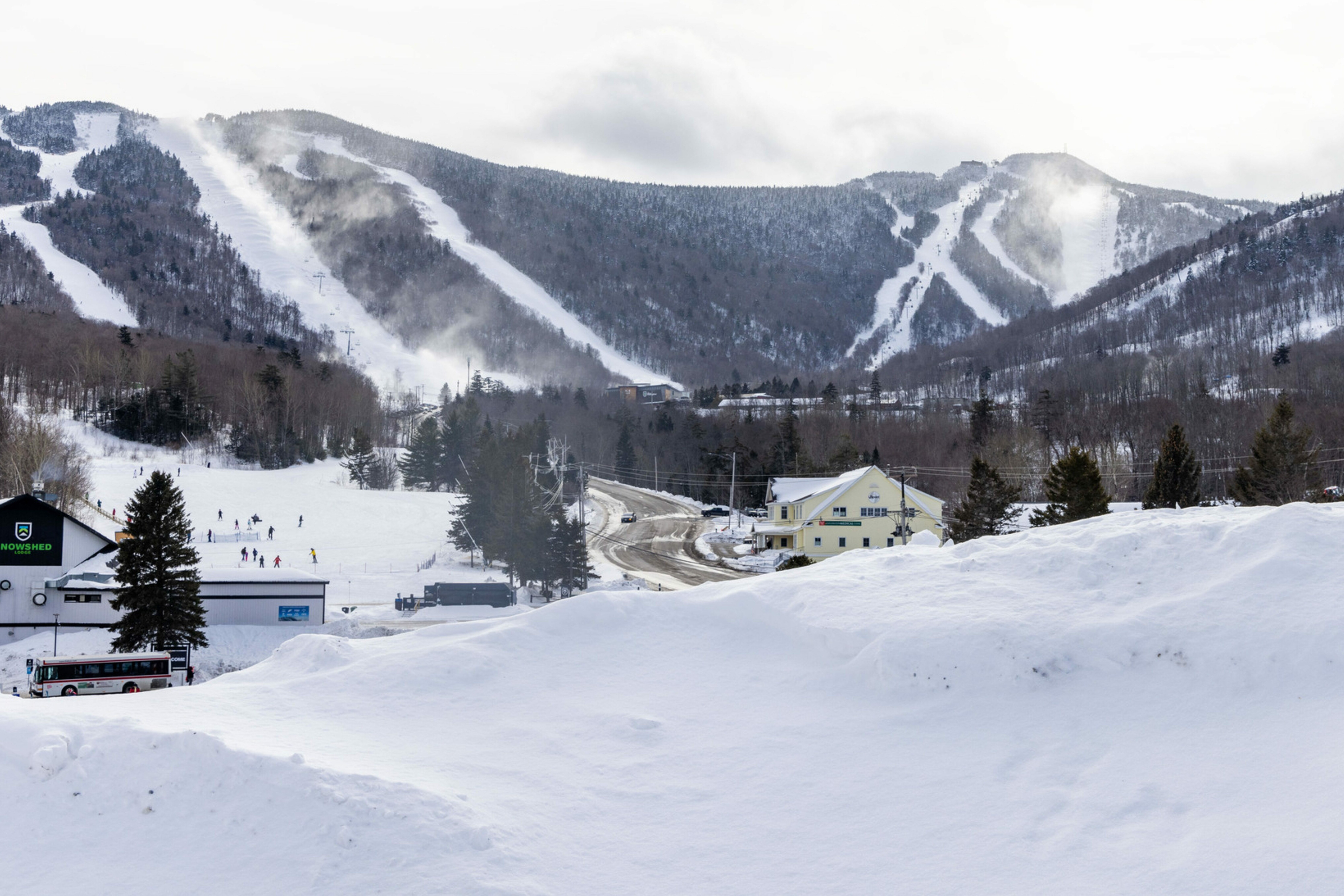 Ski slopes and snowy landscape with a road and buildings in a winter setting.