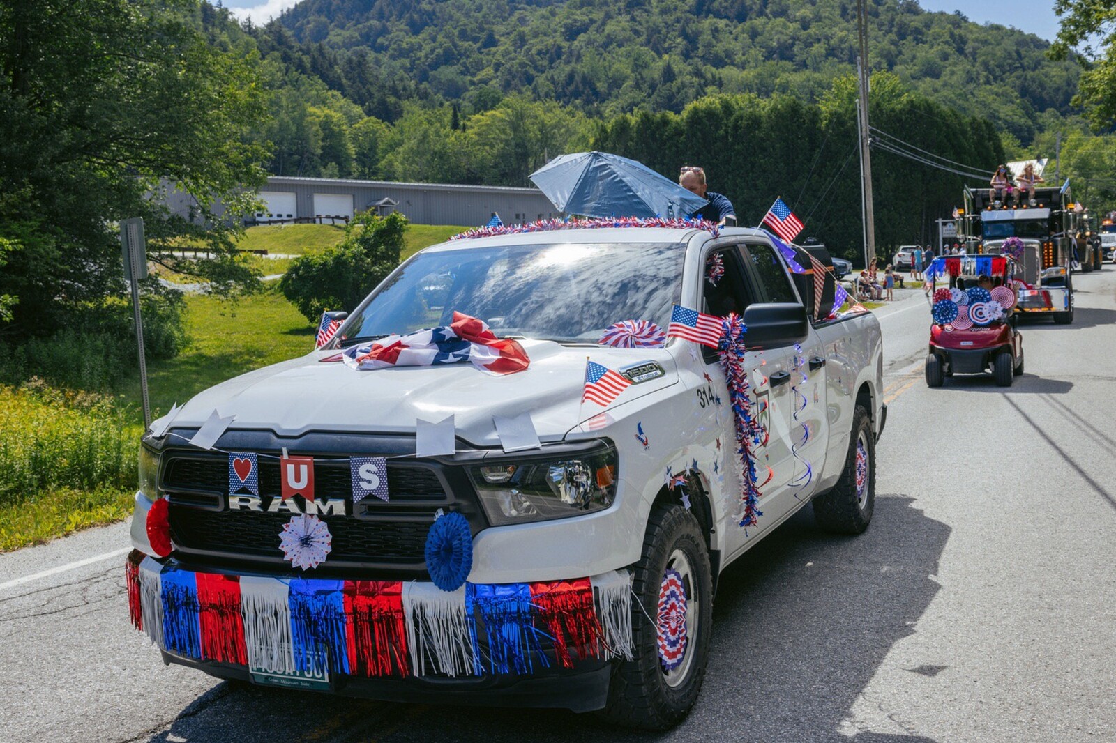 Decorated white truck with flags and streamers in a festive parade.
