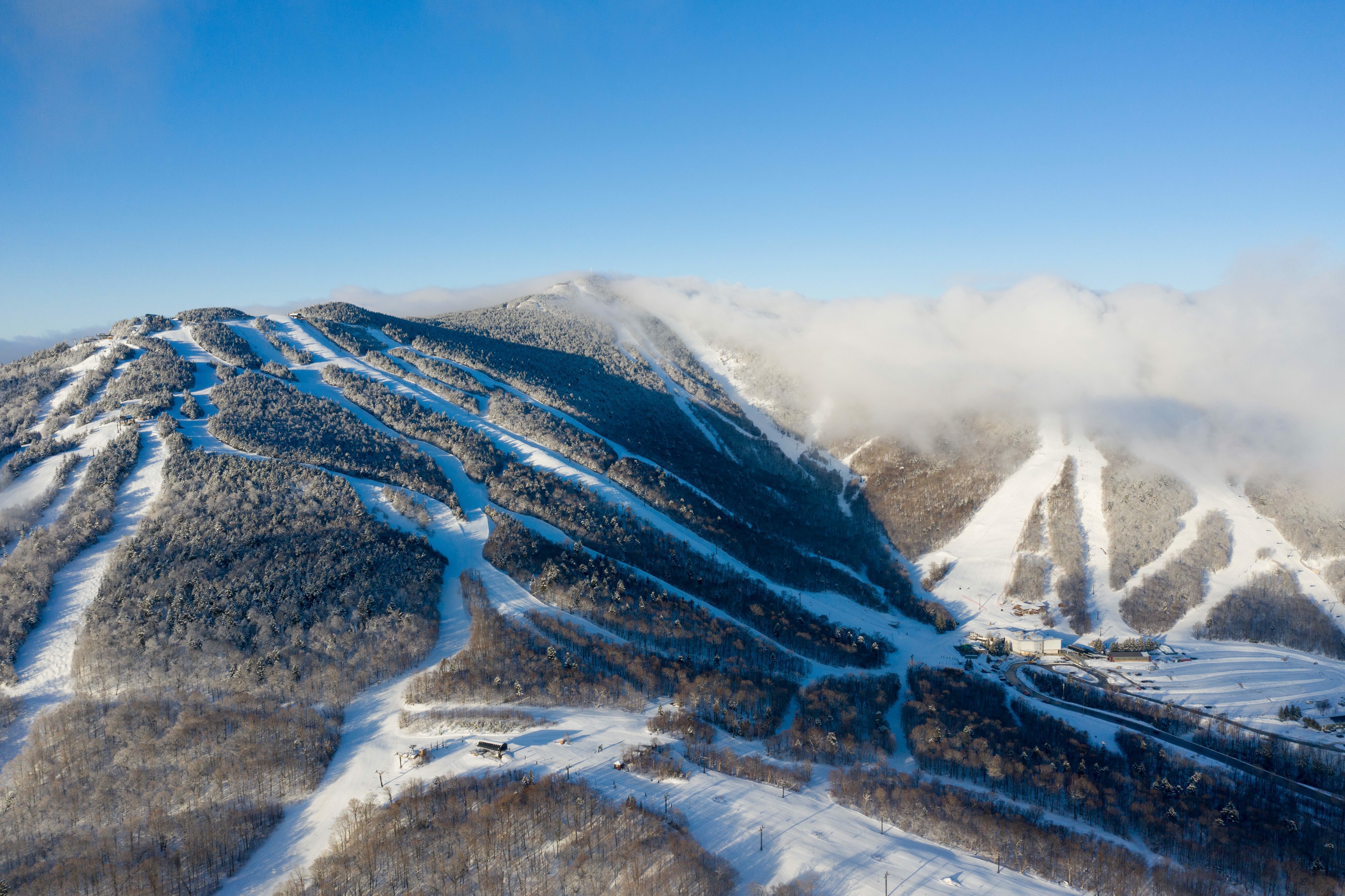 Snow-covered ski slopes on a mountain under a clear blue sky.
