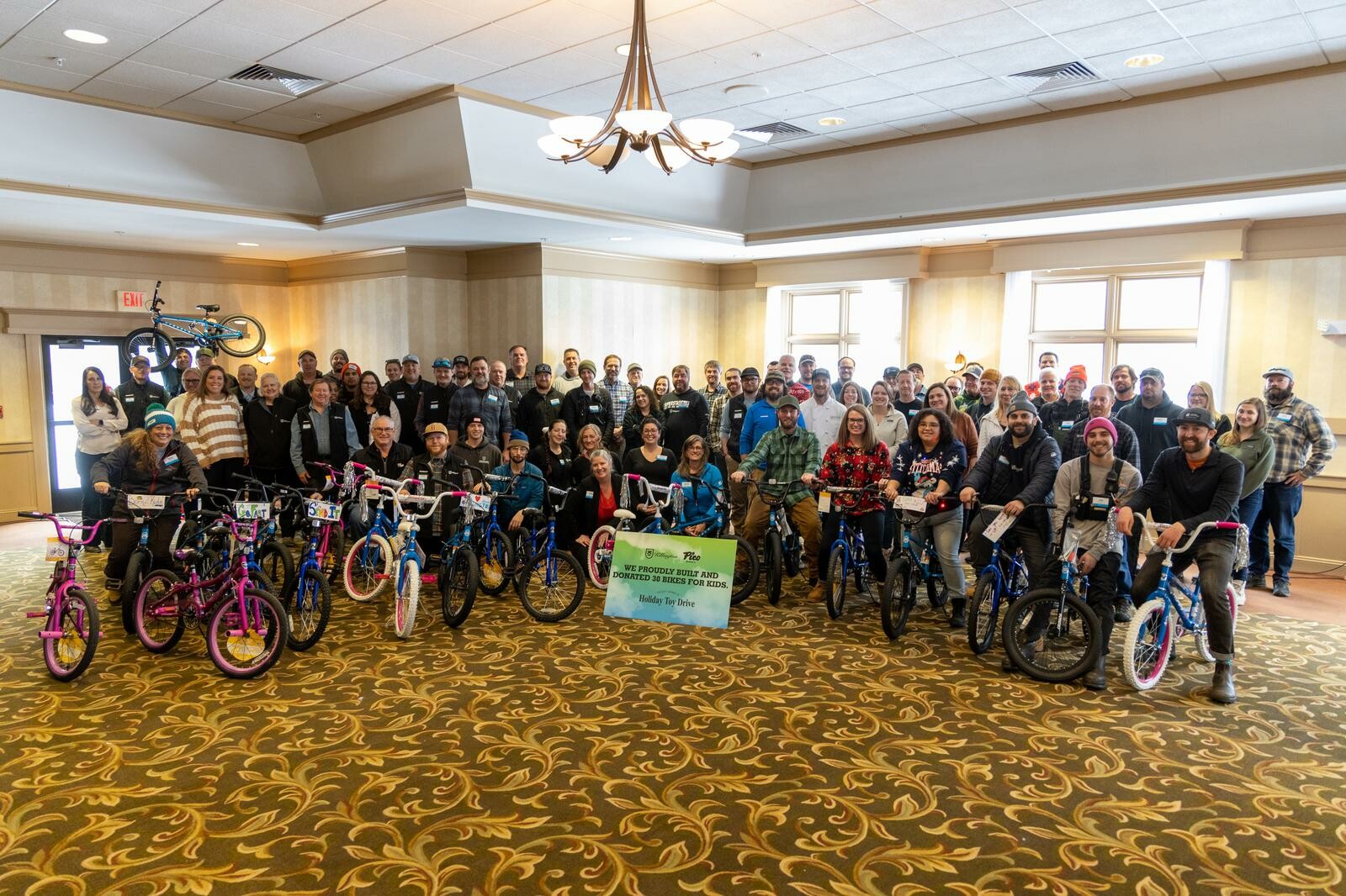 Group photo of people with donated bikes for kids at a holiday event.