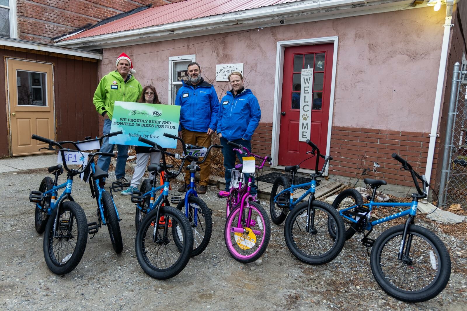 Group holding a sign next to donated bikes for a holiday toy drive.