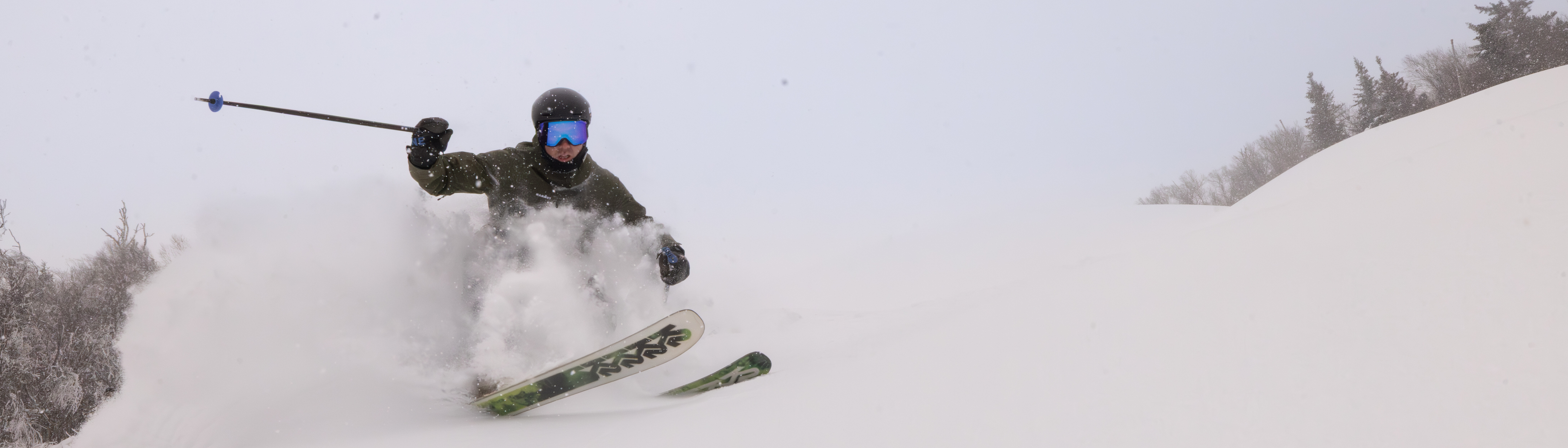 A skier glides through deep powder snow, kicking up clouds of snow.