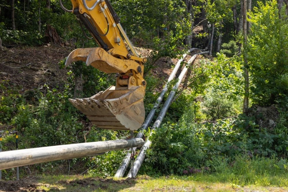 Excavator realigning piplines for snowmaking